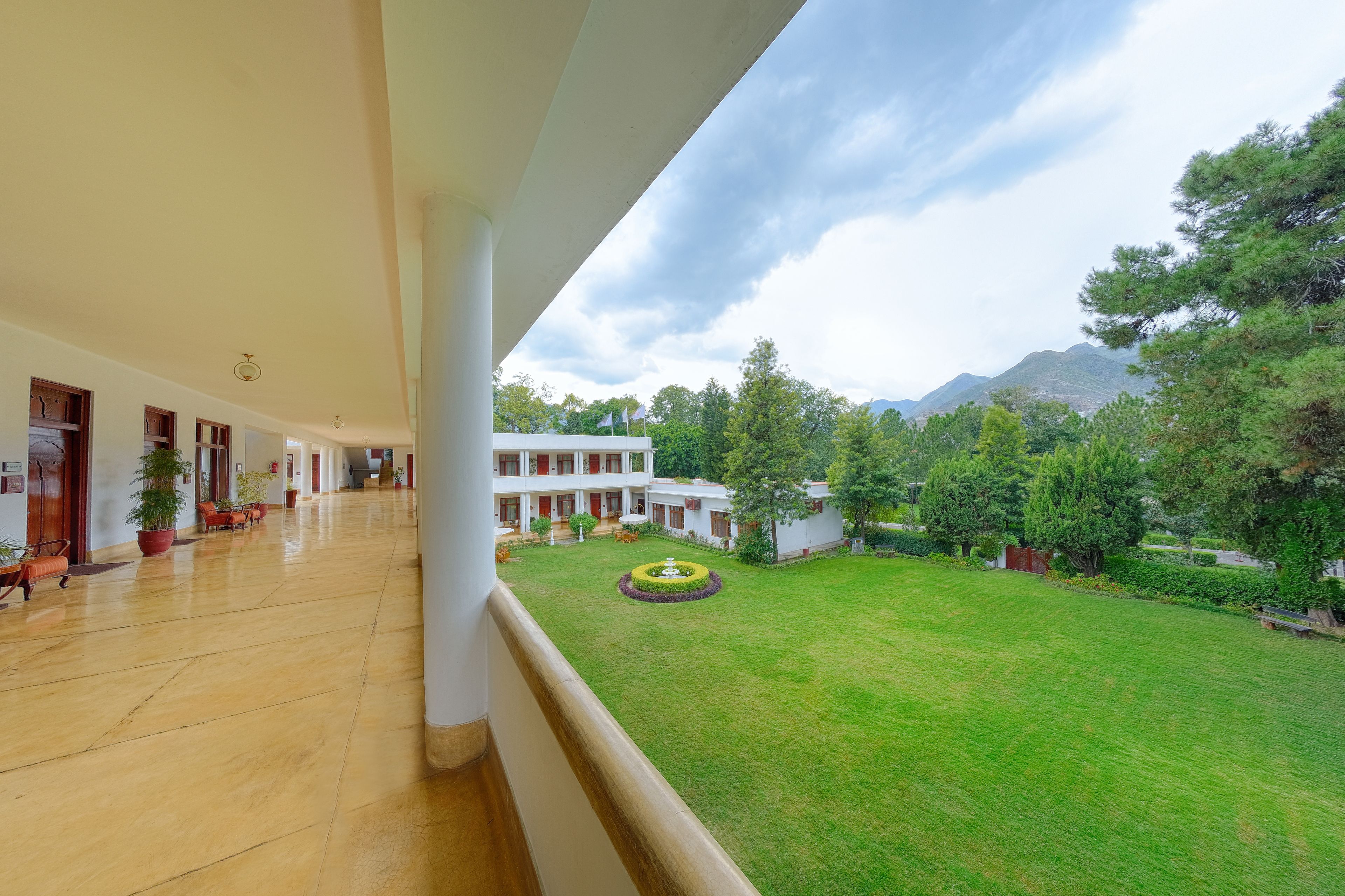 A spacious corridor with a view of a well-maintained lawn and a building with multiple windows.