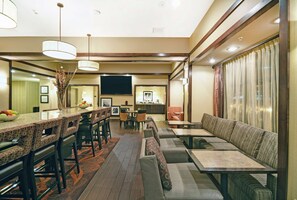 A hotel lobby with a bar area, seating, and a television. - Hampton Inn Beloit (Beloit)