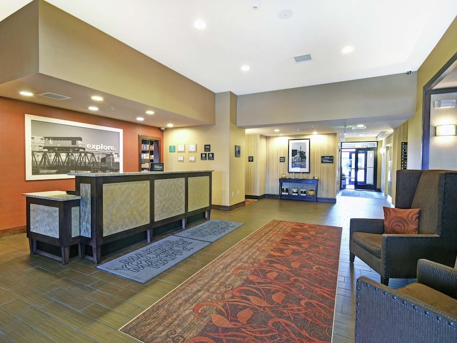 A hotel lobby with a reception desk, seating area, and a large poster on the wall.