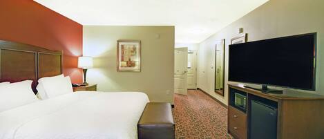 Habitación de hotel con una cama grande, un televisor de pantalla plana, un escritorio con lámpara, un microondas y un refrigerador.