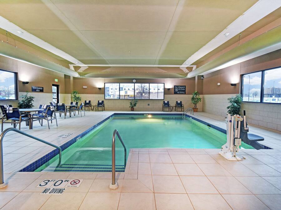 An indoor swimming pool with a 3-foot no diving sign, poolside chairs, and a lifeguard area.