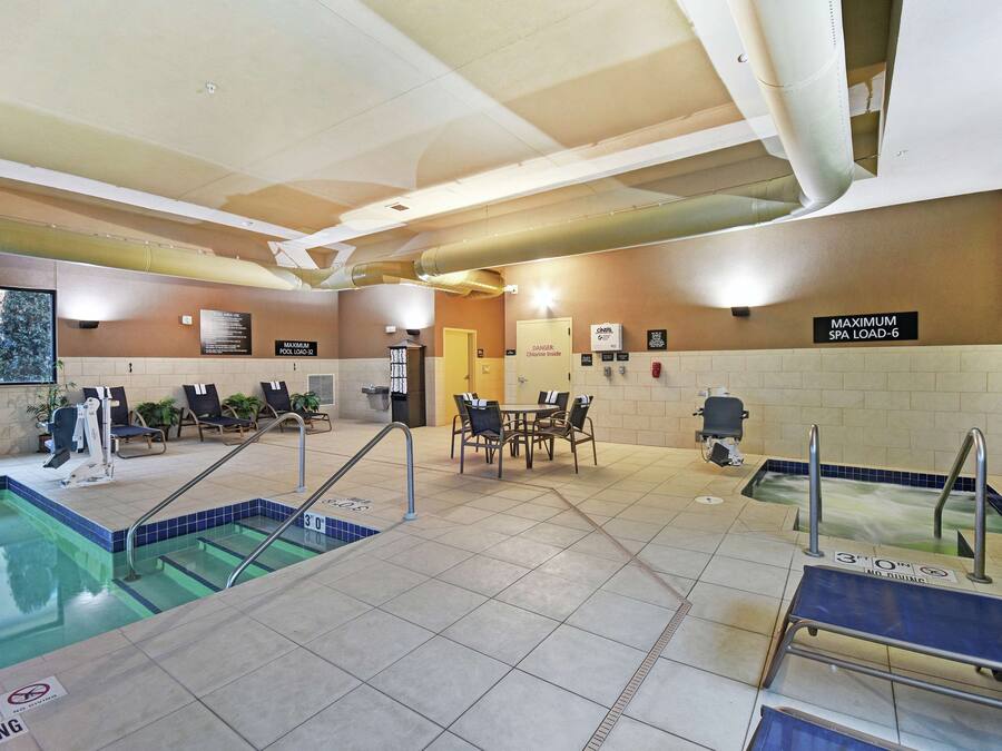 Una piscina interior con trampolín, sillas de descanso y zona de spa.