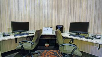 A workspace with two desks, each with a computer monitor, keyboard, and mouse. There is a printer on the central desk.