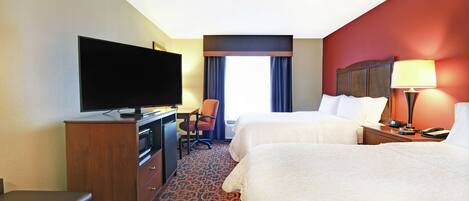 A hotel room with two beds, a TV, a desk, and a chair.