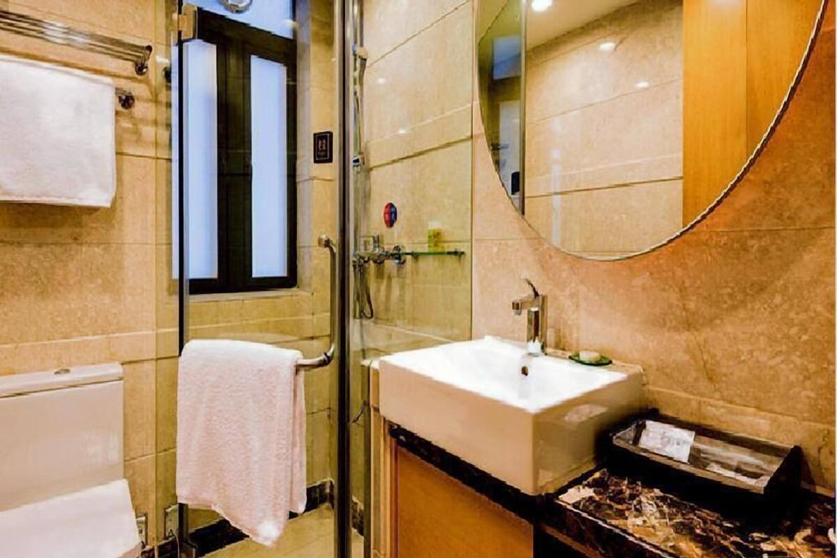 A bathroom with a glass shower enclosure, a sink, a mirror, and a towel rack.