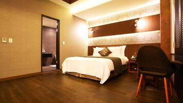 A hotel room with a large bed, a chair, a nightstand, and a mirror.