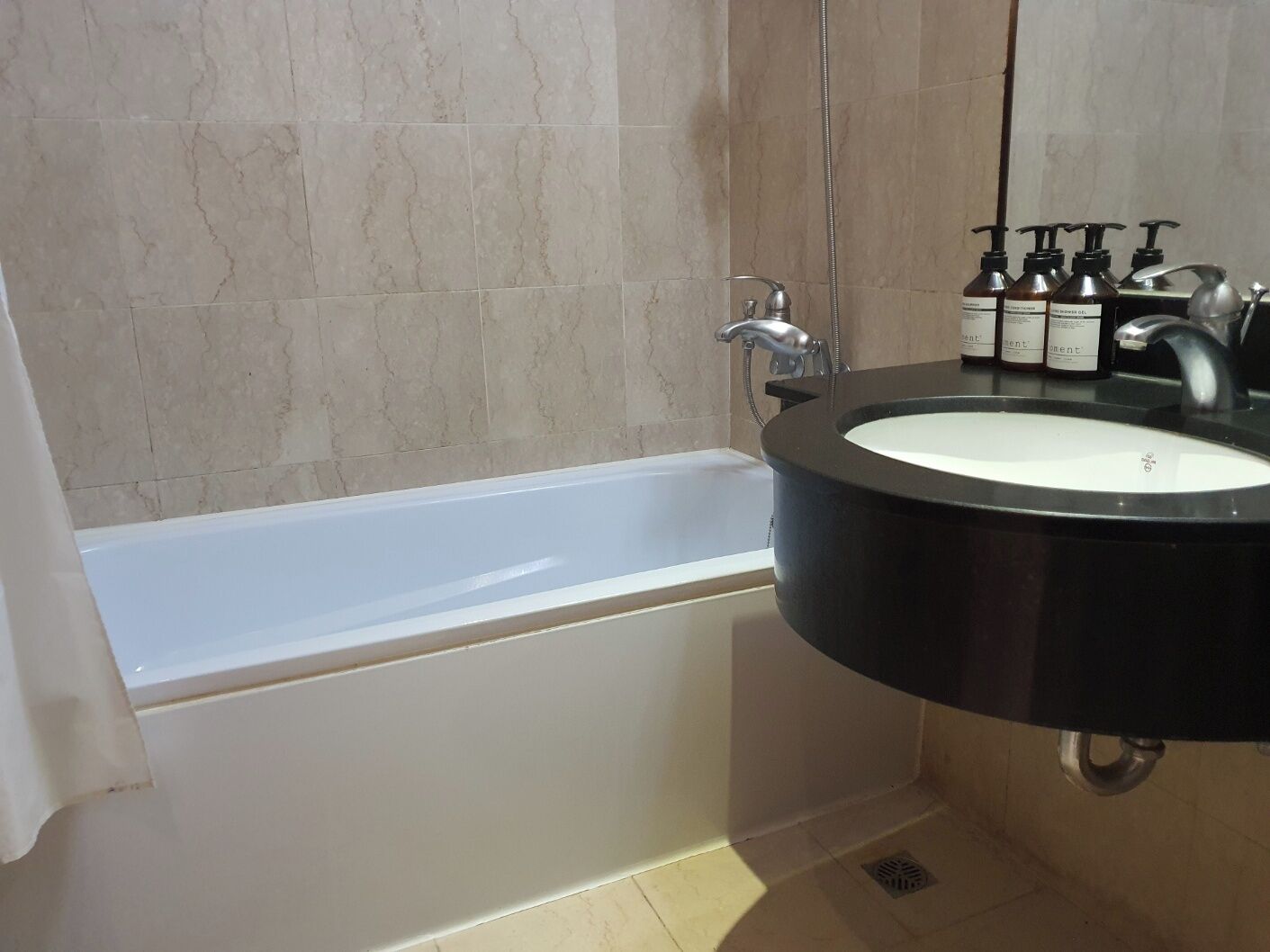 A modern bathroom with a bathtub, a black sink, and a mirror.