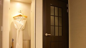 A hallway with a wooden door and a white garment hanging on a wooden hanger. - Karak Tourist Hotel (Seoul)
