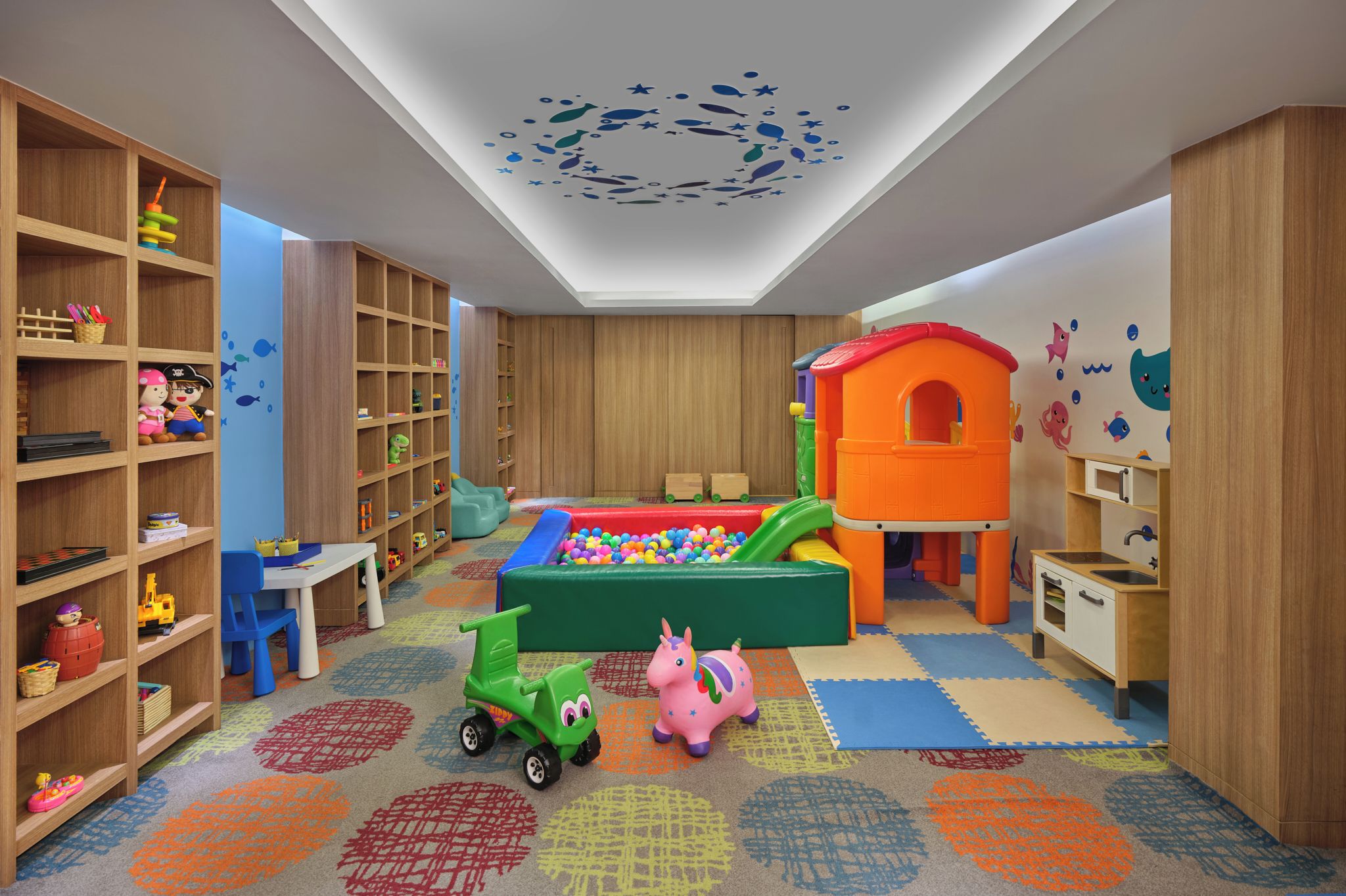 A children's playroom with a ball pit, shelves with toys, and a slide.