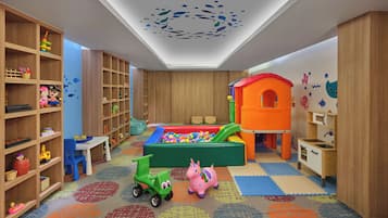A children's playroom with a ball pit, shelves with toys, and a slide.