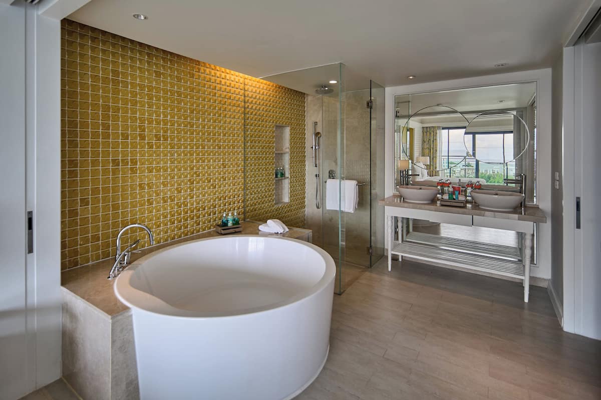 Un baño moderno con una bañera independiente grande, ducha con mampara de vidrio y tocador con un espejo amplio.