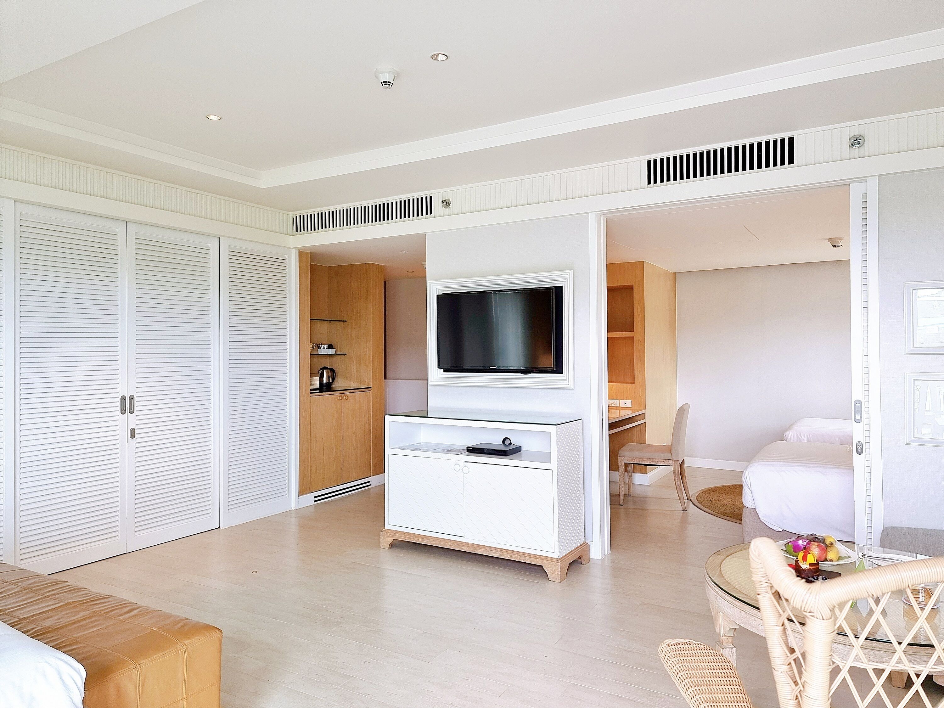 Quarto de hotel moderno com televisão, guarda-roupa e área de refeições.