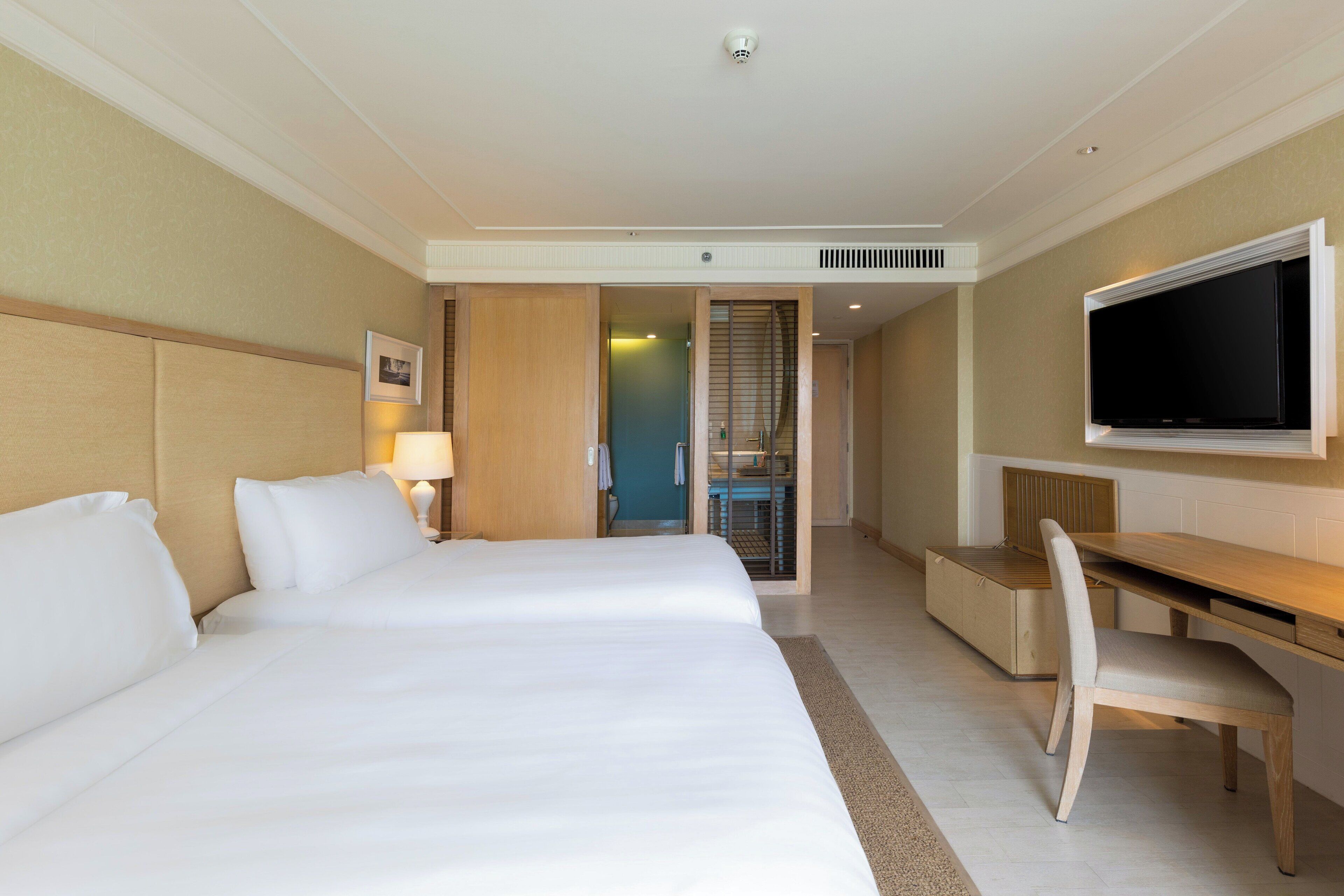 Una habitación de hotel con una cama grande, un escritorio, una silla y un televisor.