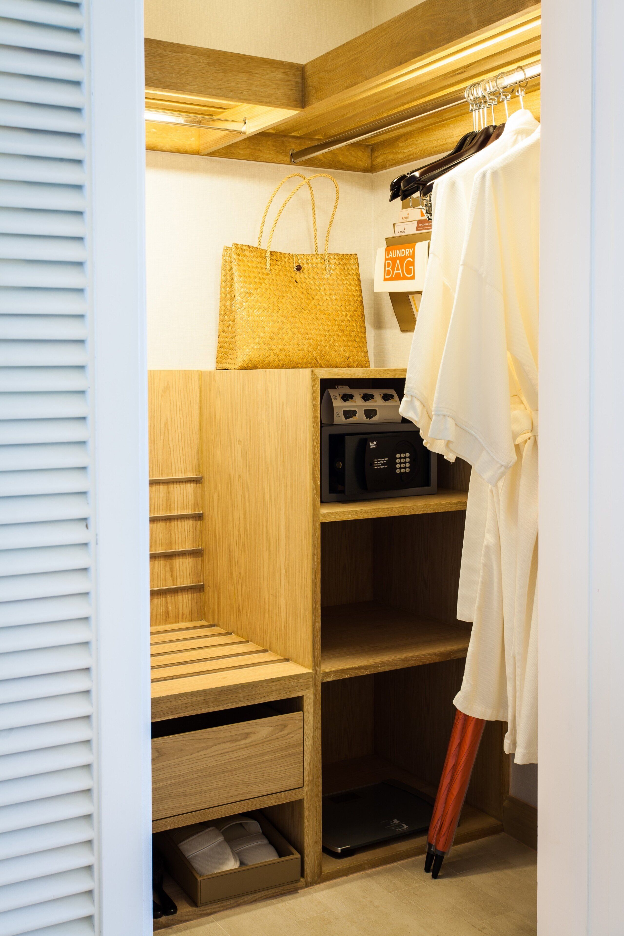 A wooden closet with a hanging bag, a microwave, and a white robe.