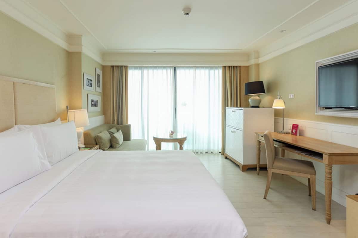 Habitación de hotel con una cama grande, un escritorio, una silla, un televisor y un mini bar.