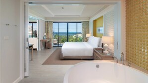 Una habitación de hotel moderna con una cama grande, una bañera y un balcón con vista al océano.
