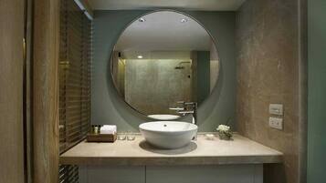 A bathroom with a round mirror, a sink, and a shower.