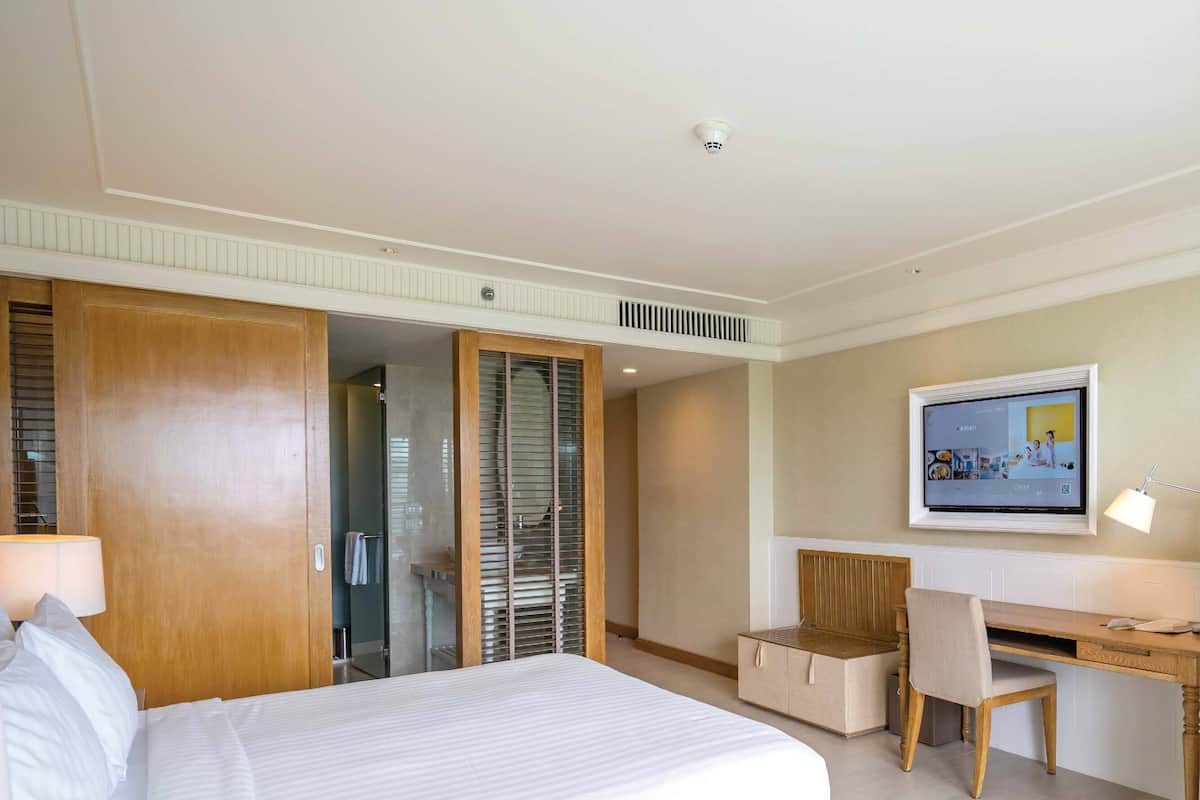 Una habitación de hotel con cama, escritorio, silla y televisor.