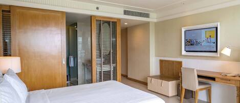 A hotel room with a bed, desk, chair, and a television.