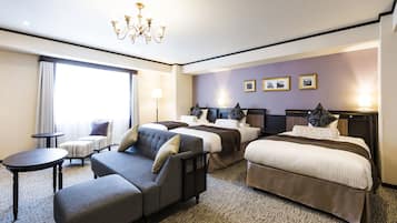 A hotel room with a large bed, a sofa, a small table, and a chandelier.