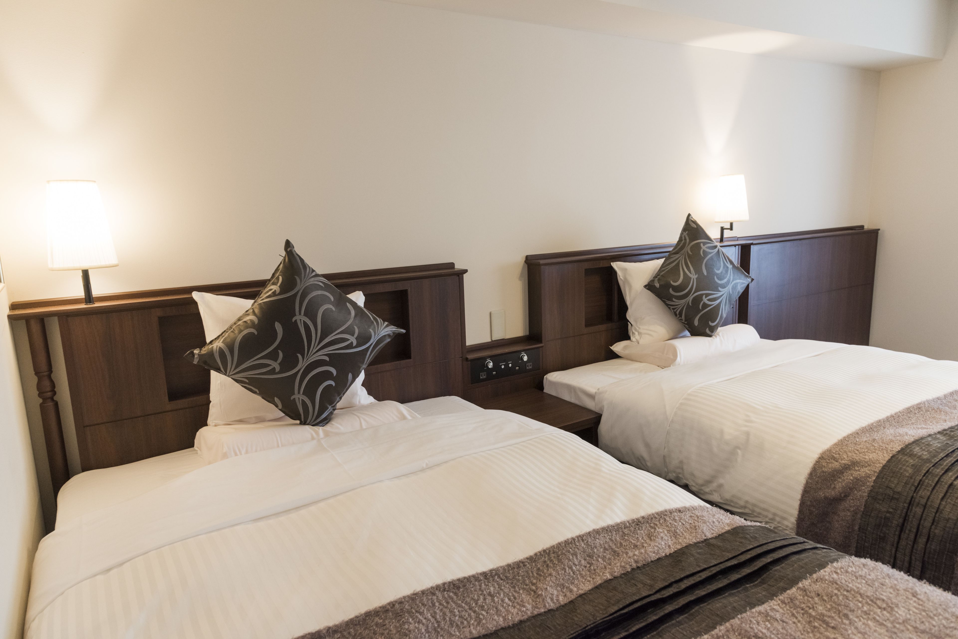 Two twin beds with headboards, bedside lamps, and decorative pillows.
