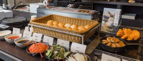 A buffet setup with various food items and a chef preparing food.