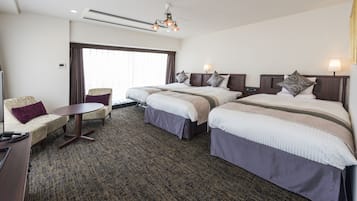 A hotel room with two beds, a sofa, a small table, and a window with curtains.