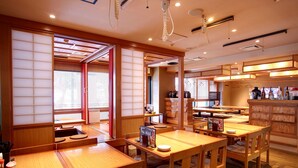Interior de un restaurante japonés tradicional con asientos en tatami, mesas de madera y puertas correderas shoji.
