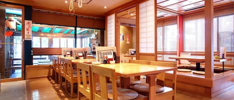 A traditional Japanese restaurant interior with wooden furniture, tatami mats, and sliding doors.