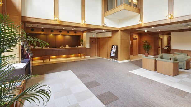 Un vestíbulo de hotel con mostrador de recepción, zona de estar y una planta grande.