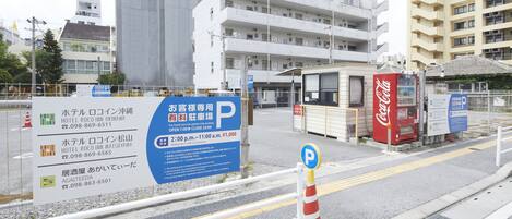 A hotel sign with multiple contact numbers and a parking sign indicating hours of operation.