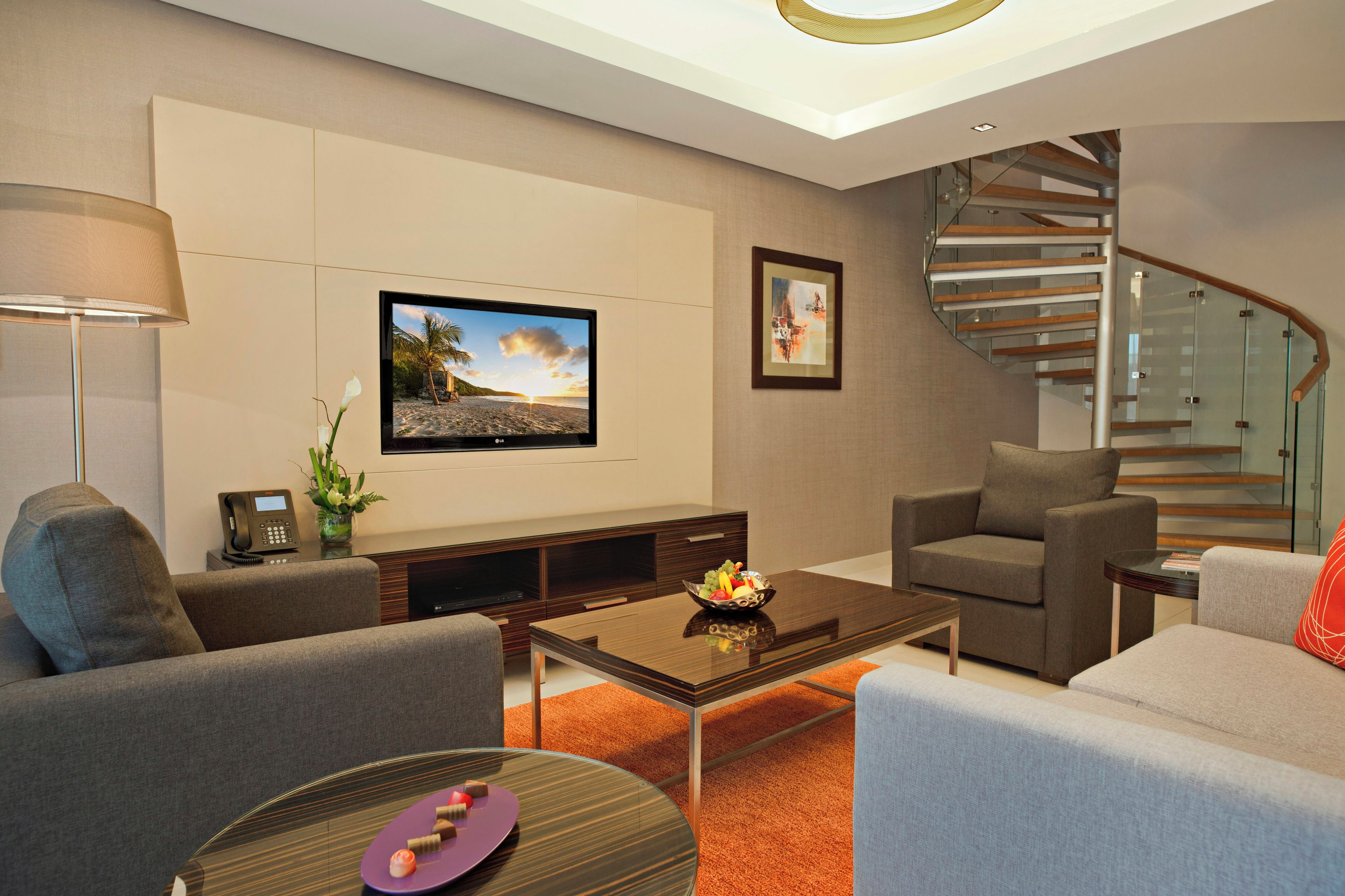 Una sala de estar moderna con un televisor de pantalla plana, una escalera y una zona de comedor.