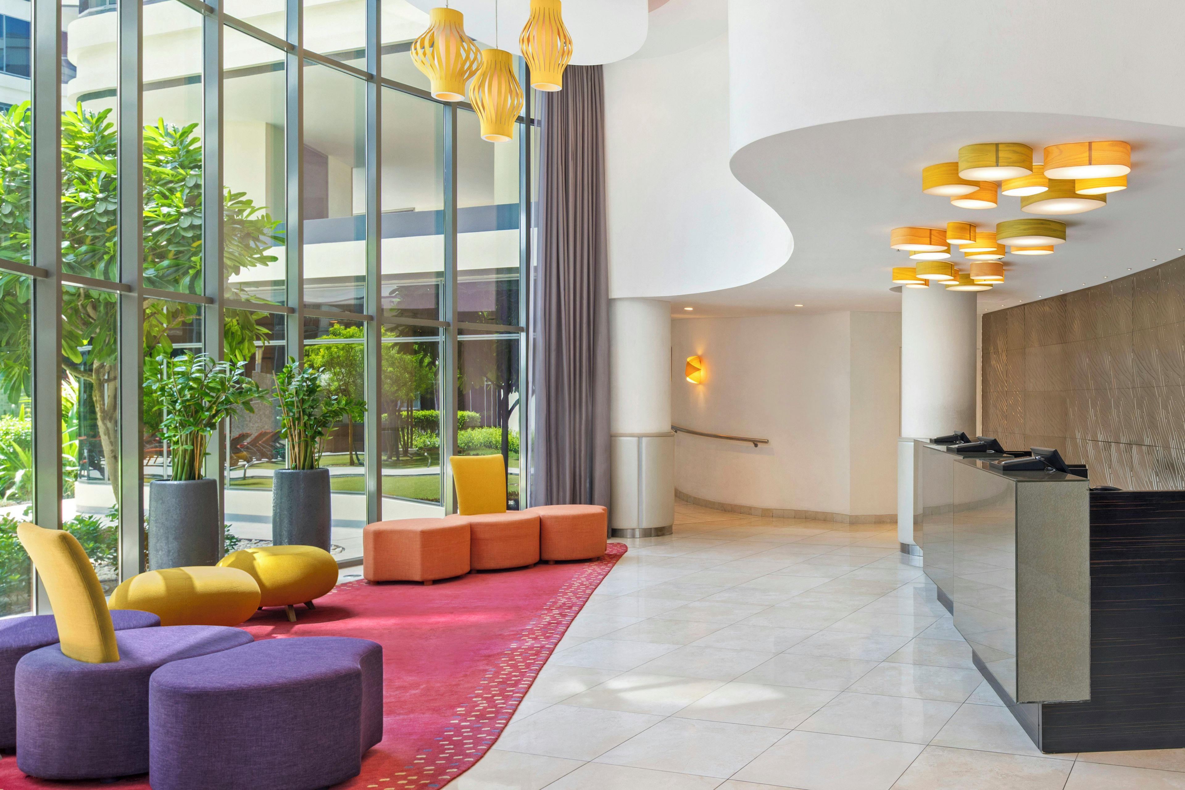 Eine moderne Lobby mit einer Rezeption, einer Sitzecke und großen Fenstern.
