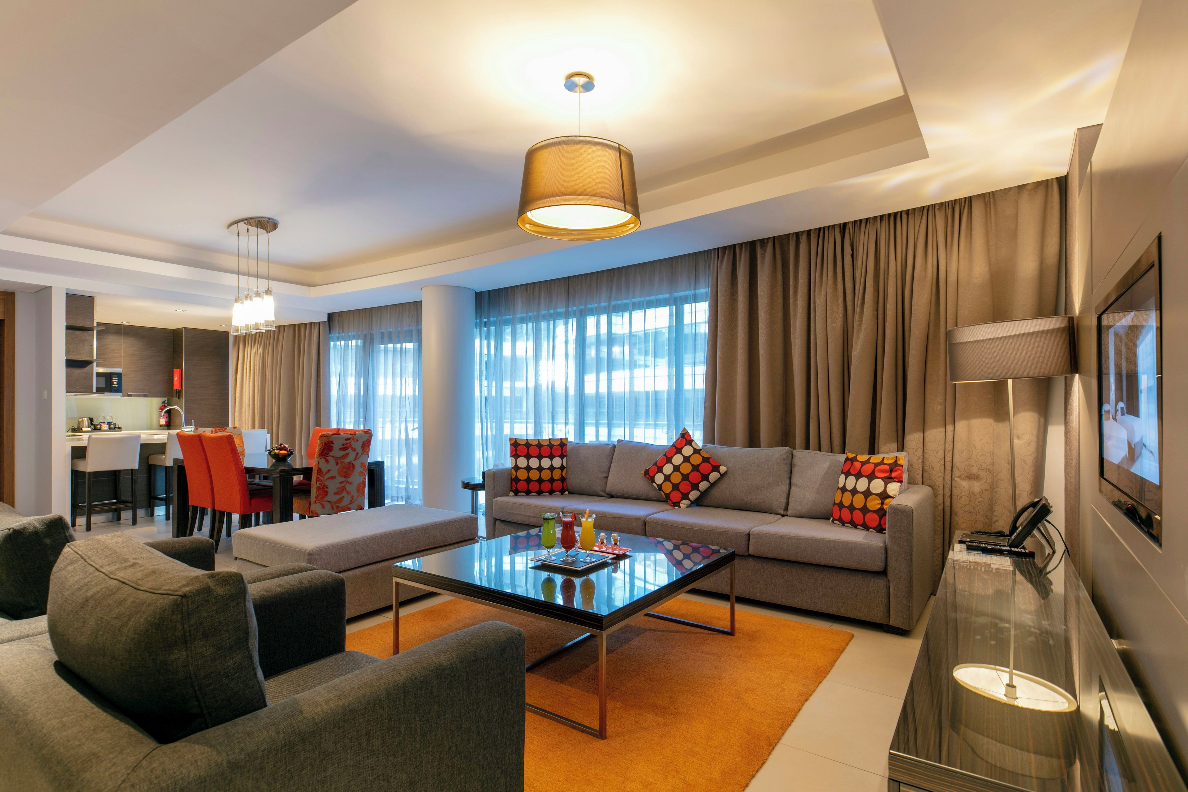 A modern living room with a sofa, armchairs, a coffee table, and a TV.