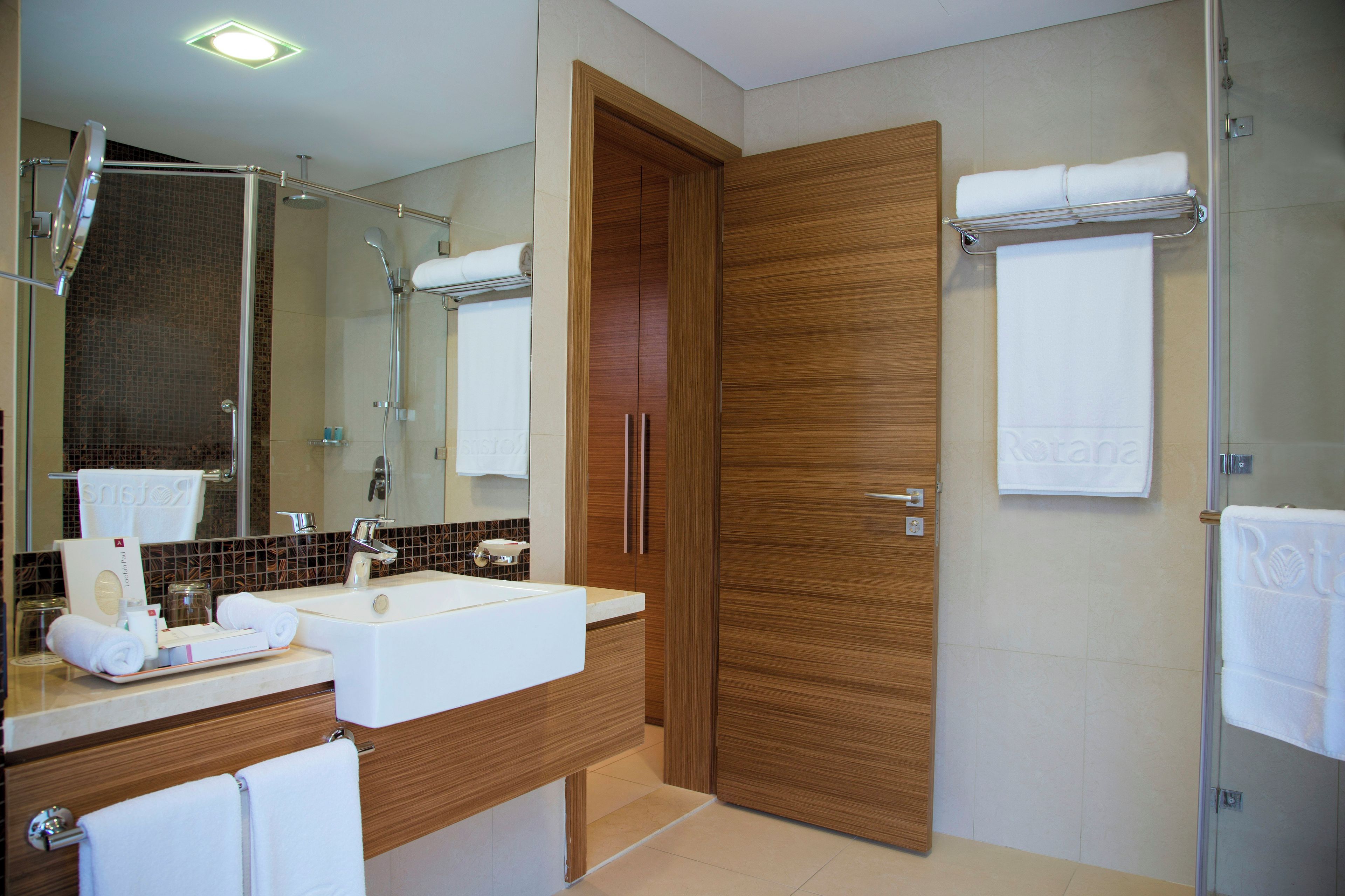 A modern bathroom with a sink, mirror, and wooden door.