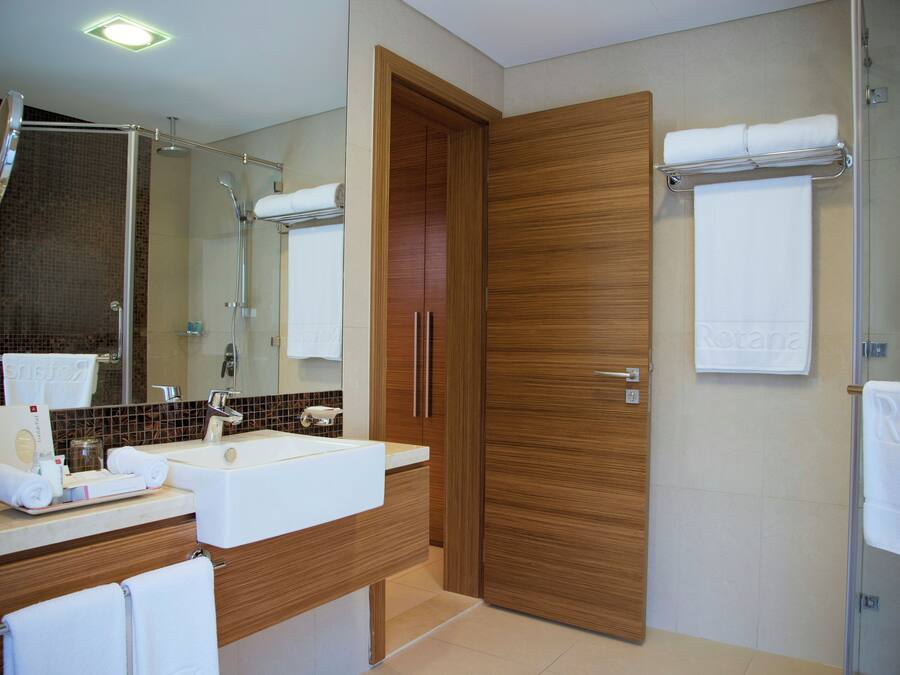 A modern bathroom with a sink, mirror, and wooden door.