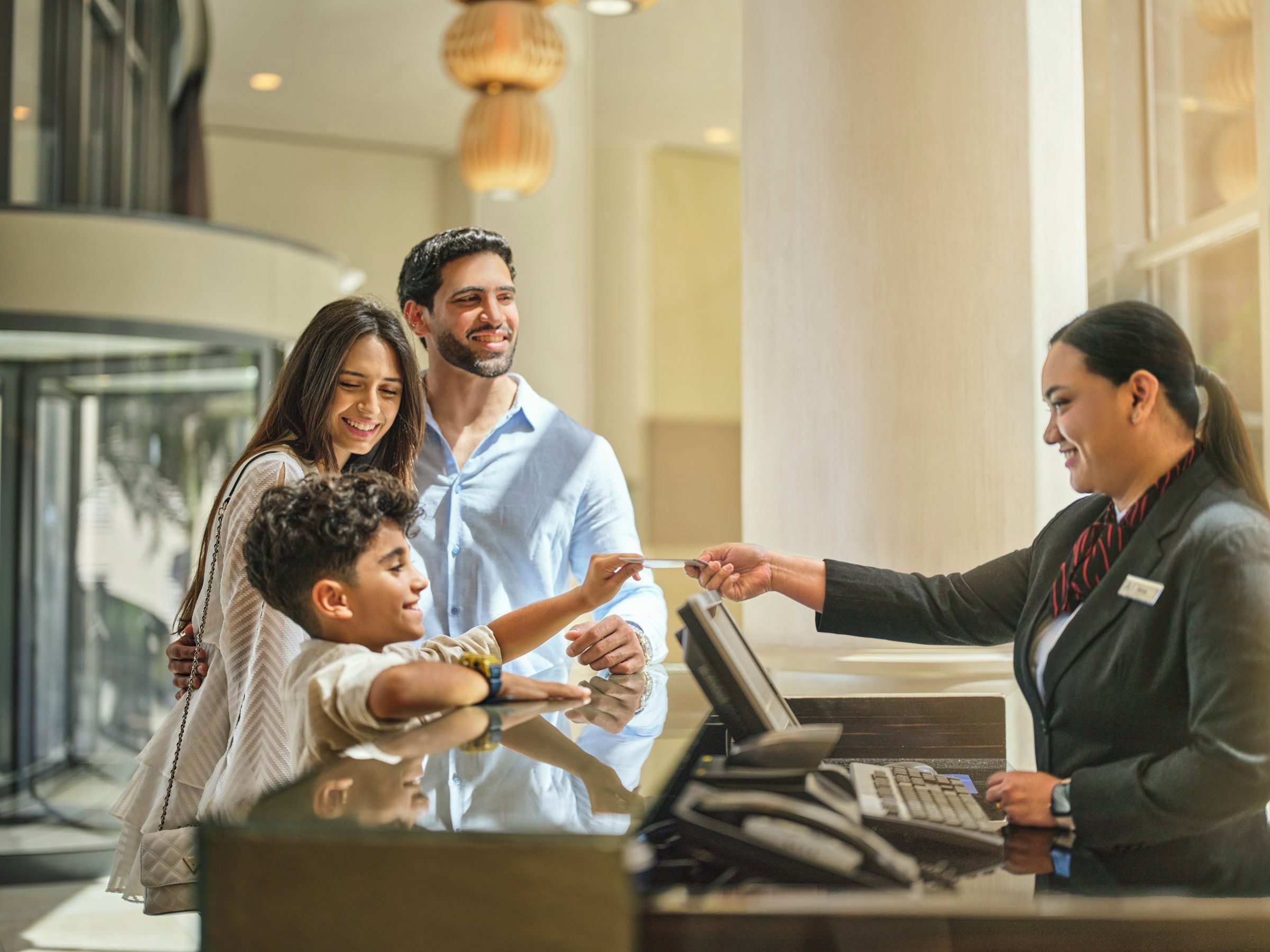 Una reception con scrivania, computer, cassa, un divisorio in vetro e un arredamento moderno.