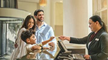 Una reception con scrivania, computer, cassa, un divisorio in vetro e un arredamento moderno.