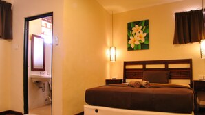 Habitación de hotel con cama, mesita de noche, lámpara de pared y un cuadro de flores.