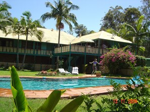 Una piscina al aire libre, sombrillas, sillones reclinables de piscina
