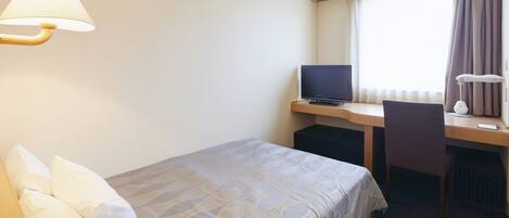 Quarto de hotel com cama, secretária com computador, cadeira, luminária, relógio e janela com cortinas.