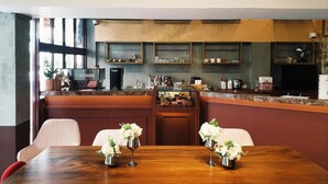 Un restaurante con barra, mesas de madera y una lámpara moderna.