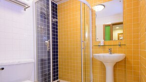 A bathroom with a white toilet, a glass-enclosed shower, and a white sink against yellow tiled walls. -  Golden House BTS Chidlom Bangkok (Bangkok)