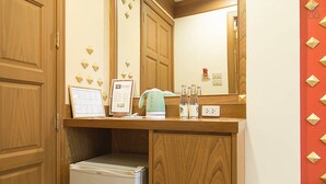 Un baño con armarios de madera, un lavamanos blanco, un espejo y un refrigerador pequeño.