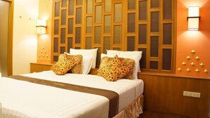 Habitación de hotel con una cama grande, dos mesitas de noche, un cabecero de madera con un diseño geométrico e iluminación empotrada en la pared.