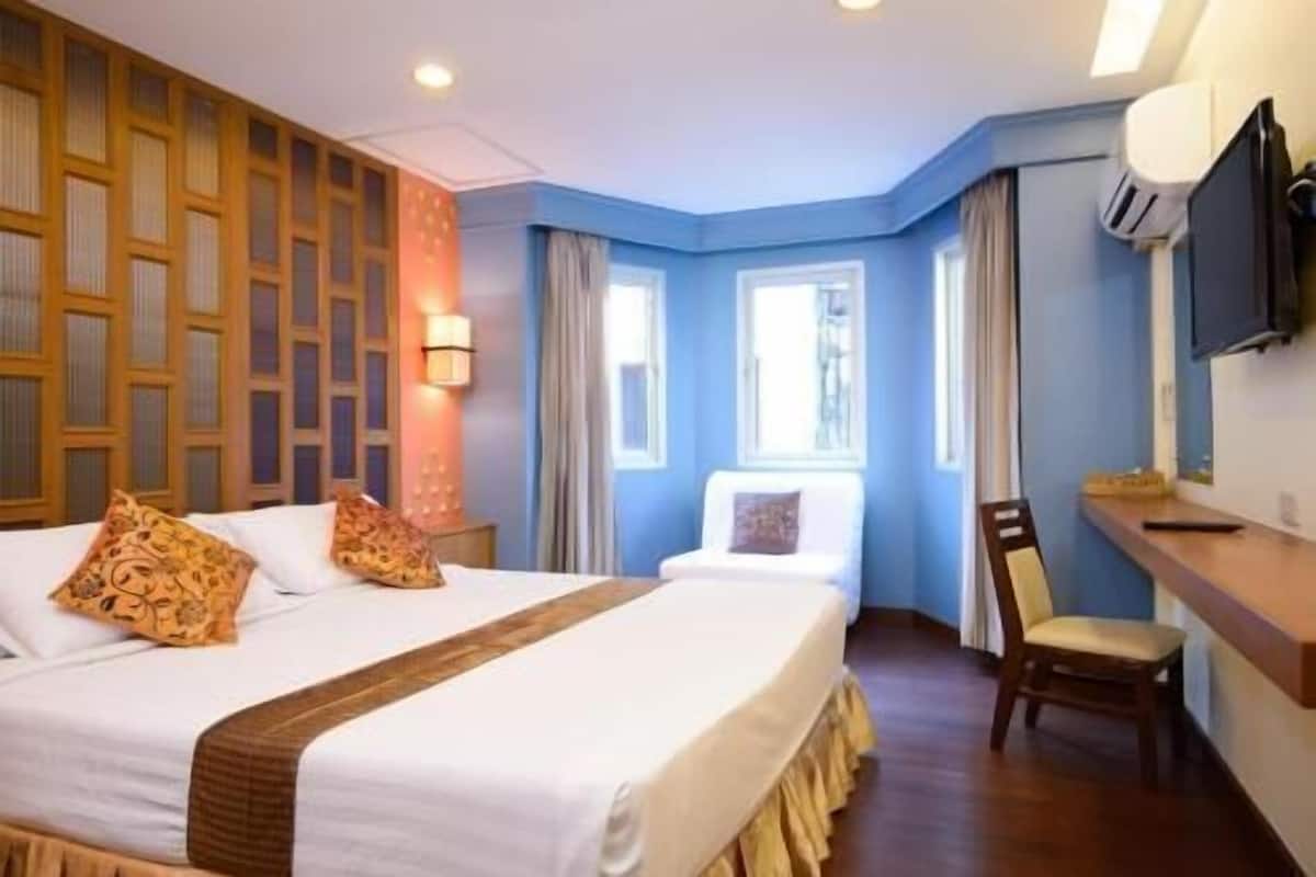 A hotel room with a large bed, a desk, a chair, and a TV.