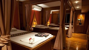 Una habitación de hotel con una cama grande, dos camas más pequeñas, un área de estar y un baño.