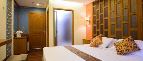 Habitación de hotel con una cama grande, un armario de madera, una mesita con una lámpara y una pared con un diseño geométrico.