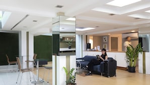 Eine moderne Hotelhalle mit Empfangsschalter, Sitzgelegenheiten und einer Küchenzeile.