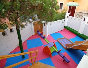 Ein Spielbereich für Kinder mit einer Wippe, einer Rutsche und einer Kletterkonstruktion.
